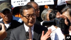 Opposition leader of Cambodia National Rescue Party Sam Rainsy, center, delivers a speech during a gathering to mark Human Rights Day, in front of National Assembly, in Phnom Penh, Cambodia, Wednesday, Dec. 10, 2014. (AP Photo/Heng Sinith)