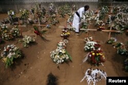 A priest arranges flowers at the site of a mass burial in Negombo, Sri Lanka, April 25, 2019.