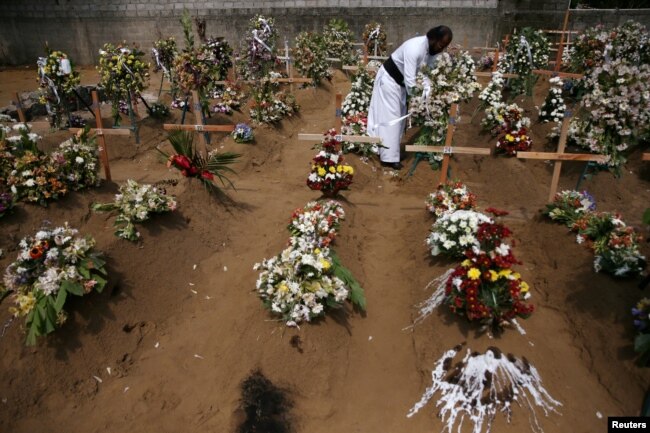 A priest arranges flowers at the site of a mass burial in Negombo, Sri Lanka, April 25, 2019.