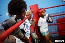 A girl looks at other children practicing on a boxing ring during an exercise session at a boxing school, in the Mare favela of Rio de Janeiro, Brazil, June 2, 2016.