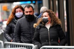 Pedestrians wear protective masks during the coronavirus pandemic in Times Square in New York, Dec. 31, 2020.