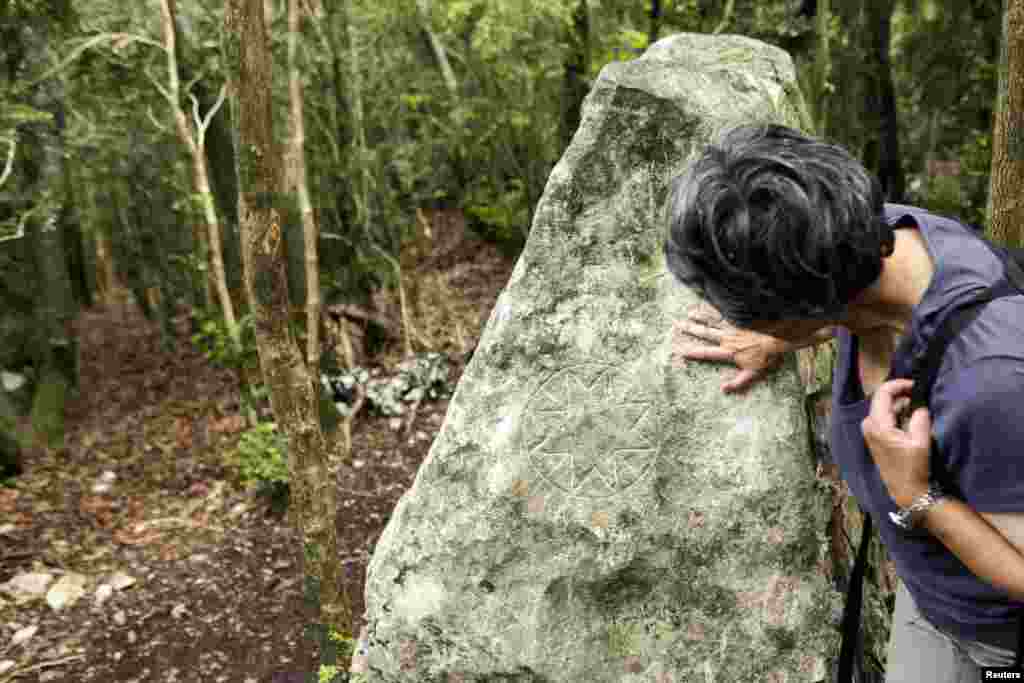 Seorang perempuan memeriksa tanda pada batu di puncak Bugarach, titik tertinggi gunung Corbieres di barat daya Perancis. (Reuters/Jean-Philippe Arles)