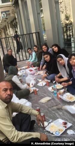 Shinabad school fire survivors and their supporters eat on a sidewalk near the Tehran office of President Hassan Rouhani, July 18, 2018.