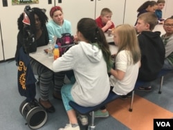 Cloe Gray goes to lunch with her classmates — virtually — at Point Pleasant Elementary School in Glen Burnie, Maryland. That's "Clo-Bot" at the head of the table. (E. Cherneff/VOA)
