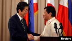 Philippine President Rodrigo Duterte and visiting Japanese Prime Minister Shinzo Abe shake hands after a joint statement at the presidential palace in Manila, Philippines, Jan. 12, 2017.