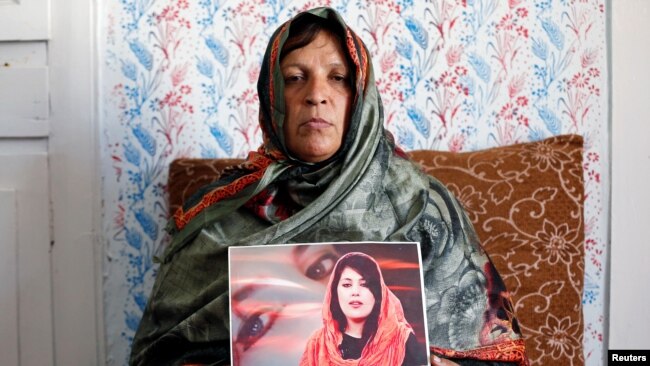 افغان صحافی مینا منگل کو مئی 2019 میں ایک حملے میں ہلاک کر دیا گیا تھا۔ اُن کی والدہ نے اُن کی ایک تصویر اُٹھا رکھی ہے۔ (فائل فوٹو)