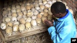 A Rwandan survivor of the 1994 genocide prays over the bones of genocide victims at a mass grave in Nyamata, Rwanda, April 2004. (AP/file photo)