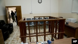 FILE - in this April 26, 2018 file photo, the defendant's cage is in the center of an empty courtroom at Nineveh Criminal Court, one of two counterterrorism courts in Iraq where suspected Islamic State militants and their associates are tried, in Tel Keif