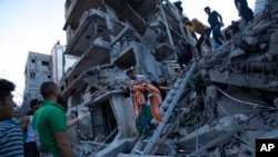 Los palestinos inspeccionan los daños del edificio destruido después de los ataques aéreos israelíes en la Franja de Gaza, el 10 de octubre de 2023. 