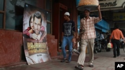 A vendor walks past a poster of Bollywood actor Salman Khan's latest movie "Bajrangi Bhaijaan" outside a theater in New Delhi, India, Aug. 11, 2015.