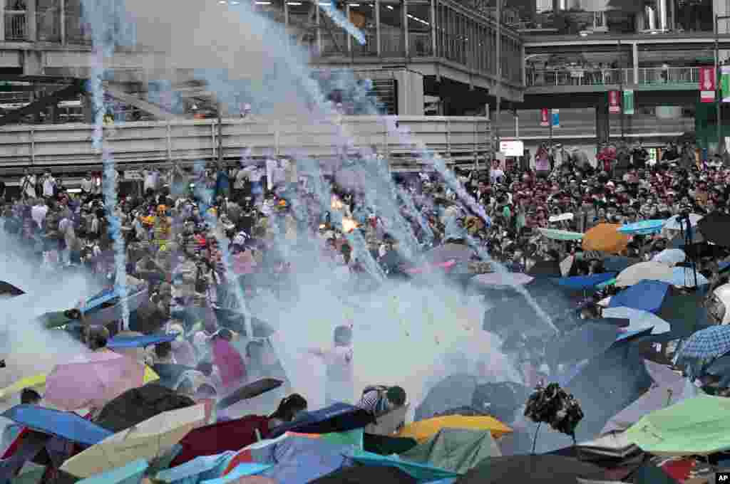 Riot police launch tear gas into the crowd as thousands of protesters surround the government headquarters in Hong Kong.