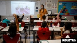 Teacher Mary Yi works with fourth grade students at the Sokolowski School, where students and teachers are required to wear masks because of the coronavirus disease (COVID-19) pandemic, in Chelsea, Massachusetts, Sept. 15, 2021.