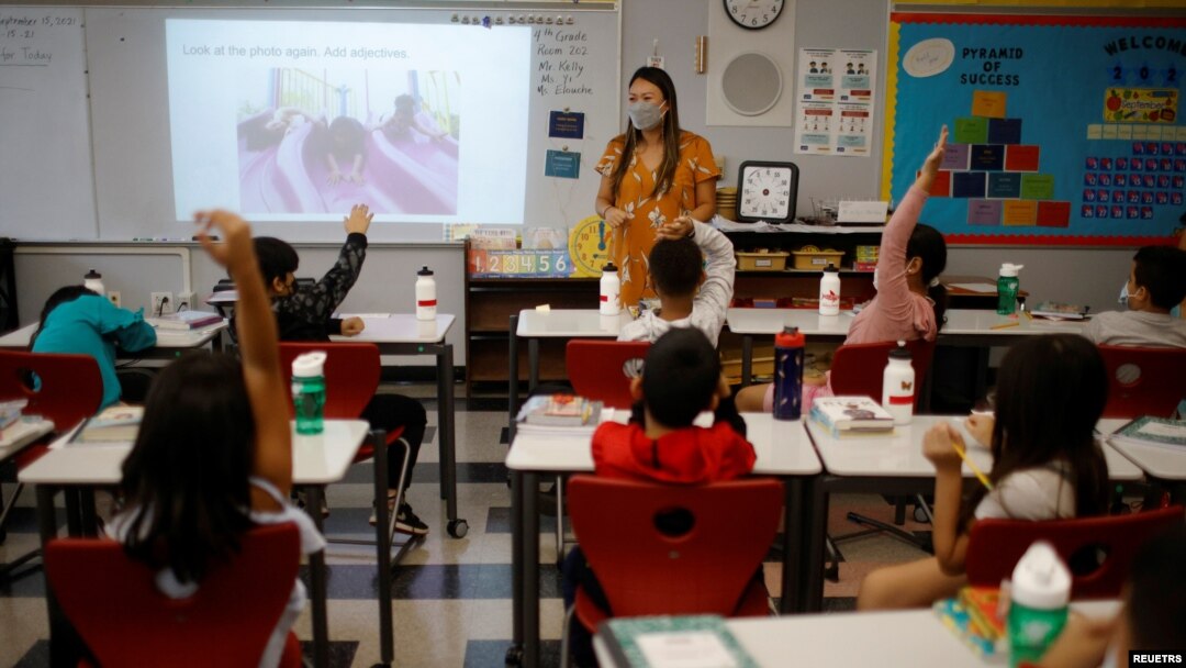Teacher Mary Yi works with fourth grade students at the Sokolowski School, where students and teachers are required to wear masks because of the coronavirus disease (COVID-19) pandemic, in Chelsea, Massachusetts, Sept. 15, 2021.