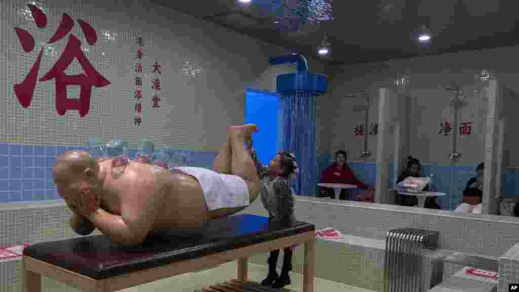 A child reaches out to touch a sculpture at a cafe with a bath house theme along the popular Wangfujing shopping street in Beijing.