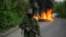 A pro-Russian separatist guards a checkpoint as tires burn behind him near the town of Slovyansk in eastern Ukraine, May 2, 2014.