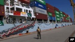 FILE - A Pakistan soldier stands guard while a loaded Chinese ship prepares to depart Gwadar port, about 700 kilometers (435 miles) west of Karachi. Pakistan, Nov. 13, 2016.
