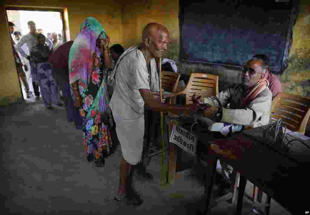 A polling official marks the finger of an elderly man with indelible ink before he casts his vote in Kunwarpur village, Uttar Pradesh, May 12, 2014.