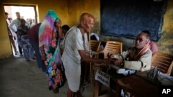 A polling official, right, marks the finger of an elderly man with indelible ink before he casts his vote at a polling station in Kunwarpur village, about 40 kilometers (25 miles) northwest of Jaunpur district, in the northern Indian state of Uttar Prades