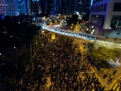 In this Sunday, Dec. 8, 2019, photo, pro-democracy protesters march into the night in central Hong Kong. Hundreds of thousands thronged Hong Kong streets.