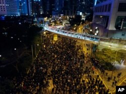 In this Sunday, Dec. 8, 2019, photo, pro-democracy protesters march into the night in central Hong Kong. Hundreds of thousands thronged Hong Kong streets.