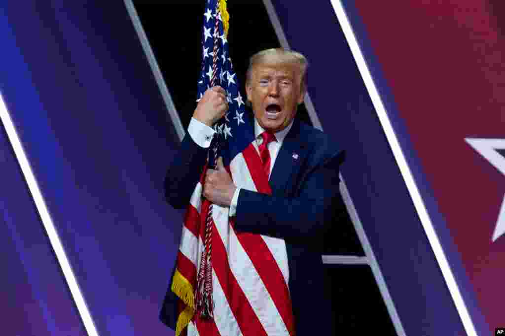 President Donald Trump hugs the American flag after speaking at Conservative Political Action Conference, CPAC 2020, at the National Harbor, in Oxon Hill, Maryland, Feb. 29, 2020.