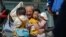 An elderly man plays with children near a commercial office building in Beijing on May 10, 2021. 