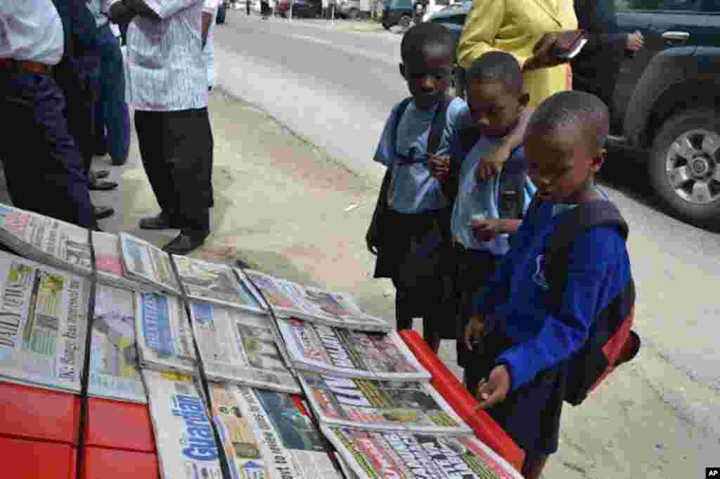 Watoto wa shule ya msingi wakisoma magazeti kwenye kibanda cha kuuza Magazeti Kivukoni Front , Dar es Sa;aam