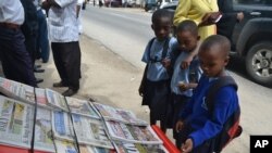 Watoto wa shule ya msingi wakisoma magazeti kwenye kibanda cha kuuza Magazeti Kivukoni Front , Dar es Salaam