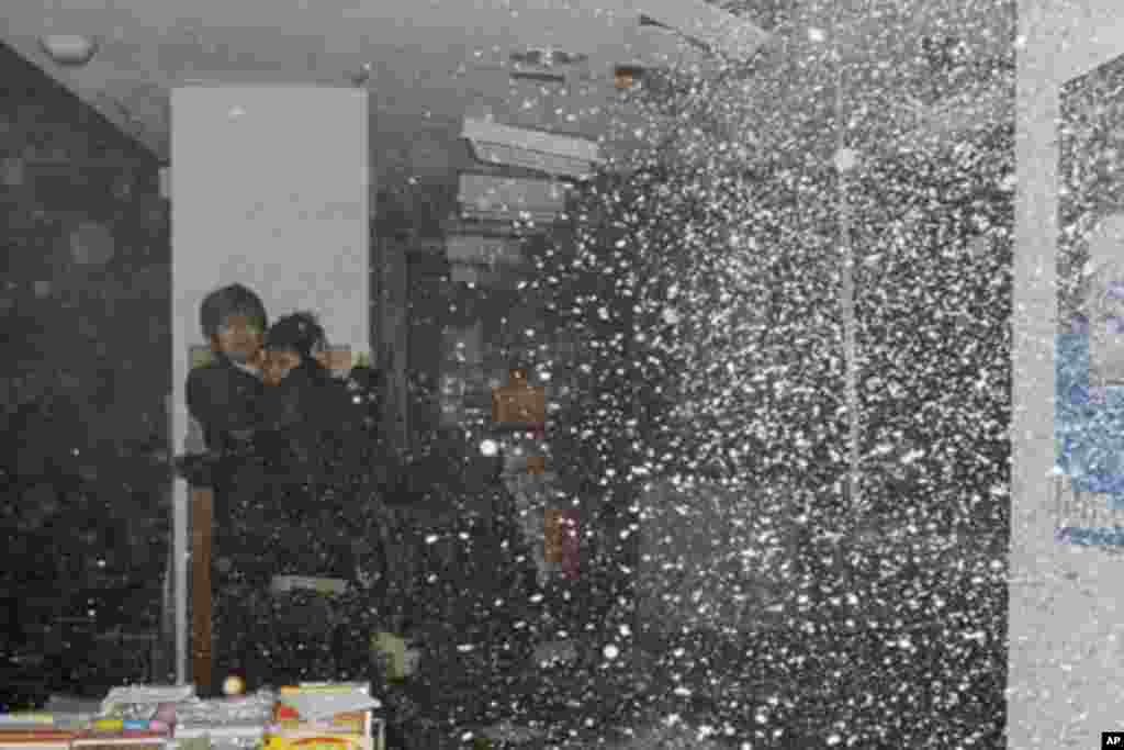 People take shelter as a ceiling collapses in a bookstore during an earthquake in Sendai, northeastern Japan, March 11, 2011 - (Reuters)