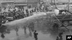 ARCHIVO - Estudiantes en Seúl, la capital de Corea del Sur, usan escudos para desafiar los intentos de dispersarlos con mangueras contra incendios el 19 de abril de 1960.