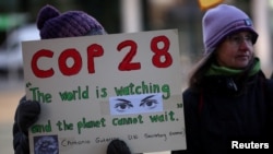 FILE - A climate activist holds a placard during a vigil to mark the opening day of the COP28 summit outside the offices of the BBC in Salford, Britain, November 30, 2023.