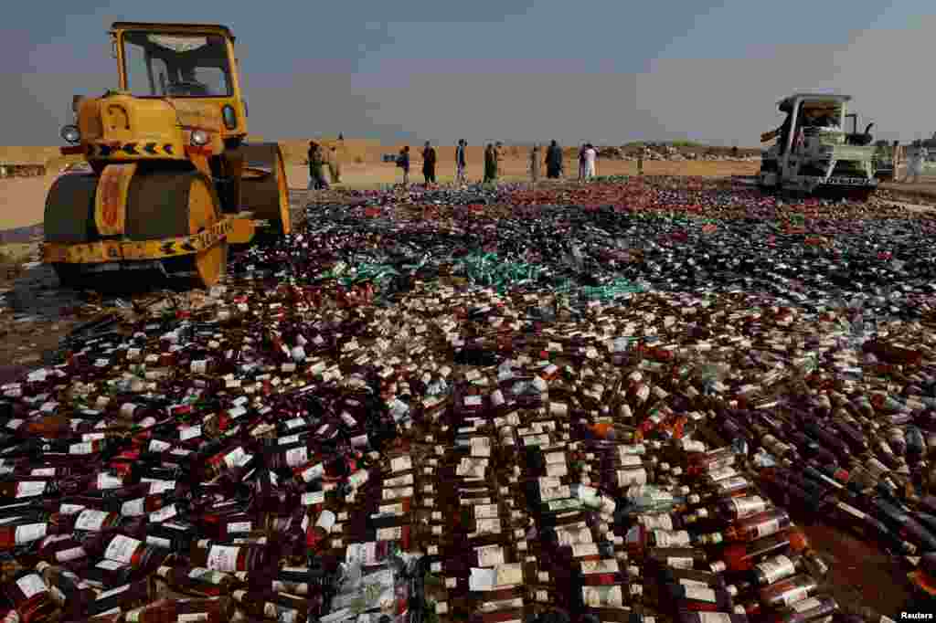 Steamrollers crush liquor bottles during a ceremony to destroy confiscated contraband and goods unfit for human consumption on the outskirts of Karachi, Pakistan.