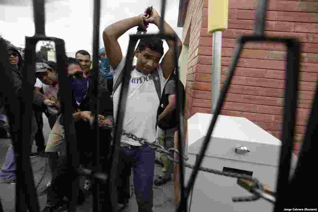 A student tries to break a lock to open a fence of the National Pedagogical University during a protest against Sunday's presidential election results in Tegucigalpa November 27, 2013.