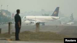 FILE - A Honduran police officer is seen against the backdrop of a plane parked at Tocontin Airport in Tegucigalpa, Honduras.