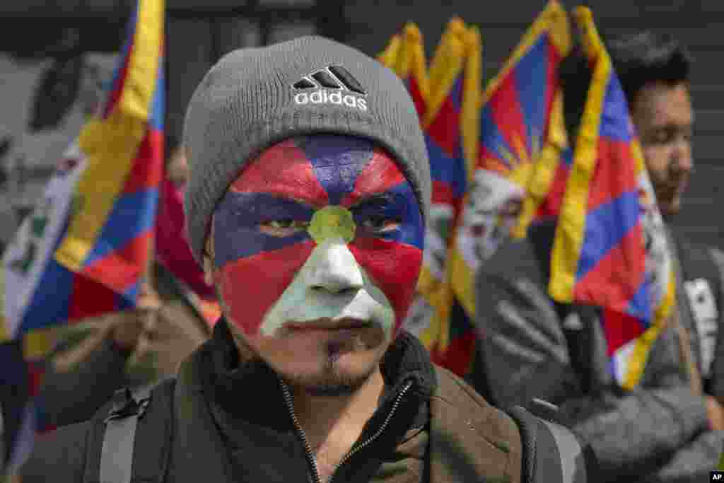 An exile Tibetan, with his face painted in the colors of the Tibetan flag, participates in a march to mark the 58th anniversary of Tibetan Uprising Day, in Dharmsala, India.