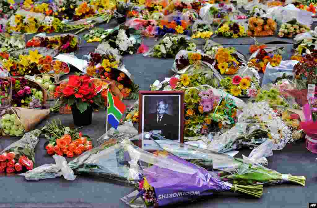 Flowers left by mourners surround a portrait of Nelson Mandela in the Sandton district of Johannesburg. Mandela, the revered icon of the anti-apartheid struggle in South Africa and one of the towering political figures of the 20th century, has died on Dec. 5, 2013. He was 85.