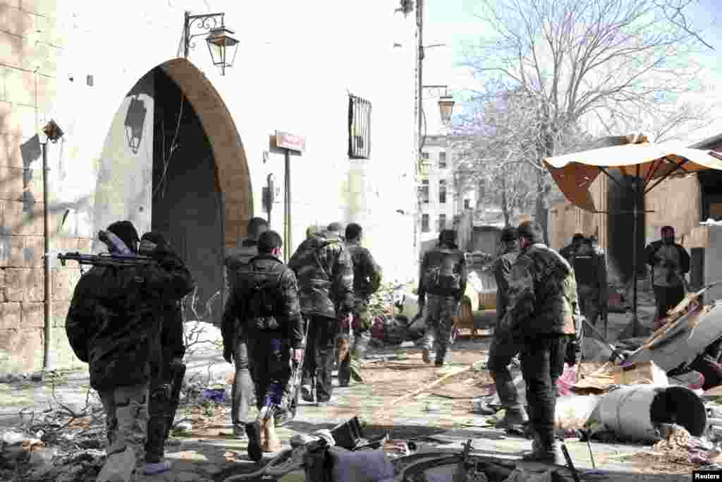 Forces loyal to Syria's President Bashar al-Assad carry their weapons as they walk along a street in the old city of Aleppo, Feb. 10, 2014. 