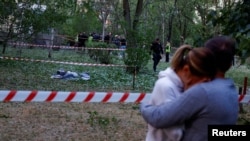 在基辅一家市医院的院区，当地居民互相拥抱安慰，旁边是一位死于俄罗斯导弹袭击的人的遗体。(2023年6月1日)