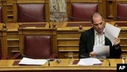 Greek Finance Minister Yanis Varoufakis reads papers during a parliament session in Athens, April 2, 2015. 