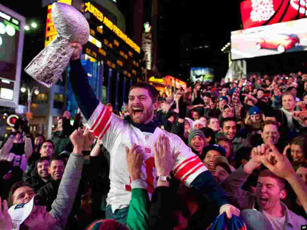 Tom Amendola, of Secaucus, N.J., celebrates a New York Giants win against the New England Patriots in the NFL football Super Bowl with a homemade trophy in Times Square, Sunday, Feb. 5, 2012, in New York.