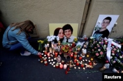 FILE - A woman kneels by a memorial on the first anniversary of the killings of the investigative reporter Jan Kuciak and his fiancee, Martina Kusnirova, in Bratislava, Slovakia, Feb. 21, 2019.
