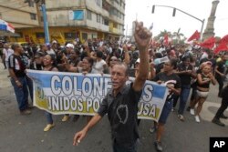 Demonstrators shouting slogans hold a banner with a message that reads in Spanish: "Colon united for the cause" in Colon, Panama, March 13, 2018.