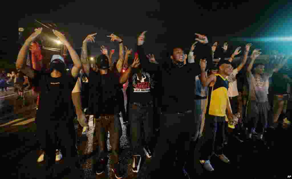 People defy a curfew, Aug. 17, 2014, before smoke and tear gas was fired to disperse a crowd protesting the shooting of teenager Michael Brown last Saturday in Ferguson, Missouri.