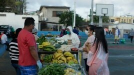 In this May 2, 2020 photo, local farmers, wearing protective as a measure to curb the spread of the new coronavirus, sell their products to residents, in San Cristobal, Galapagos Islands, Ecuador. (AP Photo/Adrian Vasquez)