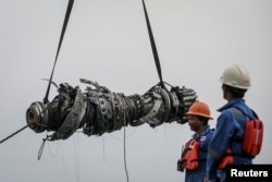 FILE - Rescue team members stand during lifting-up an turbine engine of Lion Air flight JT610 at the north coats of Karawang, Indonesia, November 3, 2018.