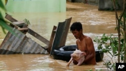 Un residente usa la cámara de una llanta para salvar a un cerdo de las inundaciones causadas por el tifón Koppu en Zaragosa, provincia de Nueva Ecija, al norte de Manila, Filipinas, el lunes, 19 de octubre de 2015.
