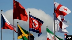 အိုလံပစ်အသင်း ကိုယ်စားပြုအလံများကြားက မြောက်ကိုရီးယားအလံ (လယ်)။