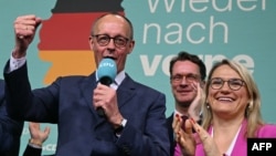 Pemimpin oposisi yang berhaluan konservatif dan Ketua Partai Uni Demokrat Kristen (CDU), Friedrich Merz (kiri) menyapa para pendukungnya setelah hasil exit poll pertama di Berlin, Jerman Minggu (23/2). 