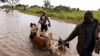 FILE - A man directs his herd of goats through a flooded section of the road from the Ugandan border into South Sudan, at Nimule, Aug. 27, 2013. Flooding in South Sudan has reached unprecedented levels in 2019, according to officials.