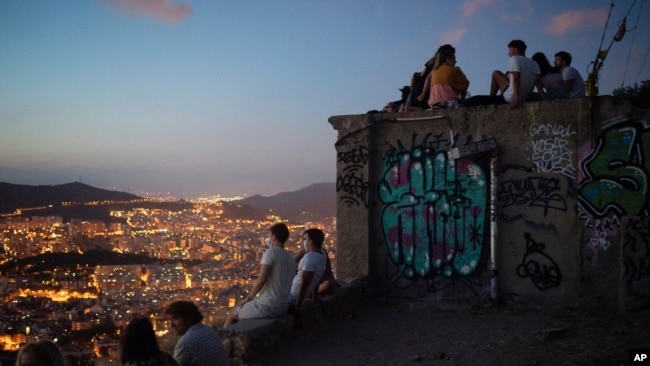 People gather outdoors at dusk on a viewpoint in Barcelona, Spain, July 25, 2020. Britain is advising people not to travel to Spain and has removed the country from the list of safe places to visit following a surge of COVID-19 cases.